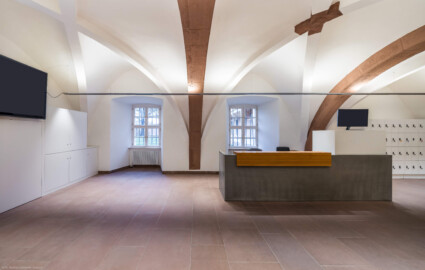 Schloss und Schlossgarten Schwetzingen - Schloss - Mittelbau - Von innen - Erdgeschoss, Nordseite - Besucherzentrum / ehemaliger Hochkeller - Von Süden - Blick vom Südende des 3. Gurtbogens von Osten nach Norden in den gewölbten Raum; im 16. Jahrhundert diente der Raum als Hofstube (eine Art Mensa), später als Hochkeller, ab 2016 als Besucherzentrum; der Boden des Raum lag früher 4 Treppenstufen tiefer, der Raum besaß Zwischenwände, ein Gewölbeschlusstein trägt die Jahreszahl 1527 (Raum: Länge x Breite: ca. 16 x 6 Meter, Höhe (bis Schlussstein): ca. 3,5 Meter; 4 Joche, 3 Gurtbögen, 3 Kreuzrippengewölbe, ein Kreuzgratgewölbe im Osten; Nordwand: 2 Fenster, 2 vermauerte Öffnungen, Standerker: 1 kleines Fenster, Südwand: 3 Türen, Westwand: verschlossene Durchgangstür) (Mittelbau: Länge Westseite ca. 45 Meter, Breite Süd-/Nordseite ca. 38 Meter; Wiederaufbau / Erweiterung: 1698-1717; Architekt: Johann Adam Breunig) (aufgenommen im November 2025, am späten Vormittag)