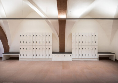 Schloss und Schlossgarten Schwetzingen - Schloss - Mittelbau - Von innen - Erdgeschoss, Nordseite - Besucherzentrum / ehemaliger Hochkeller - Von Süden - Blick von der Mitte des Raums unterhalb des 1. Gurtbogens von Osten nach Norden in den gewölbten Raum; hinter der Wand mit den Schließfächern befindet sich die Schlosskapelle; im 16. Jahrhundert diente der Raum als Hofstube (eine Art Mensa), später als Hochkeller, ab 2016 als Besucherzentrum; der Boden des Raum lag früher 4 Treppenstufen tiefer, der Raum besaß Zwischenwände, ein Gewölbeschlusstein trägt die Jahreszahl 1527 (Raum: Länge x Breite: ca. 16 x 6 Meter, Höhe (bis Schlussstein): ca. 3,5 Meter; 4 Joche, 3 Gurtbögen, 3 Kreuzrippengewölbe, ein Kreuzgratgewölbe im Osten; Nordwand: 2 Fenster, 2 vermauerte Öffnungen, Standerker: 1 kleines Fenster, Südwand: 3 Türen, Westwand: verschlossene Durchgangstür) (Mittelbau: Länge Westseite ca. 45 Meter, Breite Süd-/Nordseite ca. 38 Meter; Wiederaufbau / Erweiterung: 1698-1717; Architekt: Johann Adam Breunig) (aufgenommen im November 2025, um die Mittagszeit) Schloss und Schlossgarten Schwetzingen - Schloss - Mittelbau - Von innen - Erdgeschoss, Nordseite - Besucherzentrum / ehemaliger Hochkeller - Von Süden - Blick von der Mitte des Raums unterhalb des 1. Gurtbogens von Osten nach Norden in den gewölbten Raum; hinter der Wand mit den Schließfächern befindet sich die Schlosskapelle; im 16. Jahrhundert diente der Raum als Hofstube (eine Art Mensa), später als Hochkeller, ab 2016 als Besucherzentrum; der Boden des Raum lag früher 4 Treppenstufen tiefer, der Raum besaß Zwischenwände, ein Gewölbeschlusstein trägt die Jahreszahl 1527 (Raum: Länge x Breite: ca. 16 x 6 Meter, Höhe (bis Schlussstein): ca. 3,5 Meter; 4 Joche, 3 Gurtbögen, 3 Kreuzrippengewölbe, ein Kreuzgratgewölbe im Osten; Nordwand: 2 Fenster, 2 vermauerte Öffnungen, Standerker: 1 kleines Fenster, Südwand: 3 Türen, Westwand: verschlossene Durchgangstür) (Mittelbau: Länge Westseite ca. 45 Meter, Breite Süd-/Nordseite ca. 38 Meter; Wiederaufbau / Erweiterung: 1698-1717; Architekt: Johann Adam Breunig) (aufgenommen im November 2025, um die Mittagszeit)