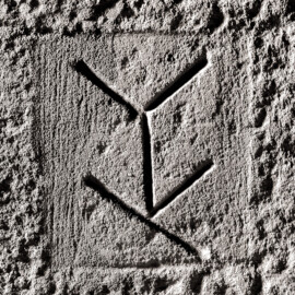 Schloss und Schlossgarten Schwetzingen - Schloss - Mittelbau - Von innen - Erdgeschoss, Nordseite - Besucherzentrum / ehemaliger Hochkeller - 2. Gurtbogen von Osten - Blick auf das 11. Steinmetzzeichen (von Süden und von unten aus gezählt) (Raum: Länge x Breite: ca. 16 x 6 Meter, Höhe (bis Schlussstein): ca. 3,5 Meter; 4 Joche, 3 Gurtbögen, 3 Kreuzrippengewölbe, ein Kreuzgratgewölbe im Osten; Nordwand: 2 Fenster, 2 vermauerte Öffnungen, Standerker: 1 kleines Fenster, Südwand: 3 Türen, Westwand: verschlossene Durchgangstür) (Mittelbau: Länge Westseite ca. 45 Meter, Breite Süd-/Nordseite ca. 38 Meter; Wiederaufbau / Erweiterung: 1698-1717; Architekt: Johann Adam Breunig) (aufgenommen im November 2025, am frühen Nachmittag) Schloss und Schlossgarten Schwetzingen - Schloss - Mittelbau - Von innen - Erdgeschoss, Nordseite - Besucherzentrum / ehemaliger Hochkeller - 2. Gurtbogen von Osten - Blick auf das 11. Steinmetzzeichen (von Süden und von unten aus gezählt) (Raum: Länge x Breite: ca. 16 x 6 Meter, Höhe (bis Schlussstein): ca. 3,5 Meter; 4 Joche, 3 Gurtbögen, 3 Kreuzrippengewölbe, ein Kreuzgratgewölbe im Osten; Nordwand: 2 Fenster, 2 vermauerte Öffnungen, Standerker: 1 kleines Fenster, Südwand: 3 Türen, Westwand: verschlossene Durchgangstür) (Mittelbau: Länge Westseite ca. 45 Meter, Breite Süd-/Nordseite ca. 38 Meter; Wiederaufbau / Erweiterung: 1698-1717; Architekt: Johann Adam Breunig) (aufgenommen im November 2025, am frühen Nachmittag)