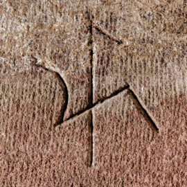 Schloss und Schlossgarten Schwetzingen - Schloss - Mittelbau - Von innen - Nördöstliches Treppenhaus - Untergeschoss / Tür zum Besucherzentrum - Von Westen - Blick auf das Steinmetzzeichen am vorderen Sandsteinblock der Fragmente des ehemaligen achteckigen Treppenturms (Mittelbau: Länge Westseite ca. 45 Meter, Breite Süd-/Nordseite ca. 8 Meter; Wiederaufbau / Erweiterung: 1698-1717; Architekt: Johann Adam Breunig) (aufgenommen im November 2025, am frühen Nachmittag) Schloss und Schlossgarten Schwetzingen - Schloss - Mittelbau - Von innen - Nördöstliches Treppenhaus - Untergeschoss / Tür zum Besucherzentrum - Von Westen - Blick auf das Steinmetzzeichen am vorderen Sandsteinblock der Fragmente des ehemaligen achteckigen Treppenturms (Mittelbau: Länge Westseite ca. 45 Meter, Breite Süd-/Nordseite ca. 8 Meter; Wiederaufbau / Erweiterung: 1698-1717; Architekt: Johann Adam Breunig) (aufgenommen im November 2025, am frühen Nachmittag)