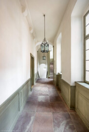 Schloss und Schlossgarten Schwetzingen - Schloss - Mittelbau - Von innen - Nördöstliches Treppenhaus, 1. Obergeschoss - Von Westen - Blick von der Tür zum Credenzzimmer nach Osten in den Gang; links die Tür zum ersten Vorzimmer, rechts der Bildmitte die Treppe zum 2. Obergeschoss (Mittelbau: Länge Westseite ca. 45 Meter, Breite Süd-/Nordseite ca. 38 Meter; Wiederaufbau / Erweiterung: 1698-1717; Architekt: Johann Adam Breunig) (aufgenommen im November 2025, am frühen Nachmittag) Schloss und Schlossgarten Schwetzingen - Schloss - Mittelbau - Von innen - Nördöstliches Treppenhaus, 1. Obergeschoss - Von Westen - Blick von der Tür zum Credenzzimmer nach Osten in den Gang; links die Tür zum ersten Vorzimmer, rechts der Bildmitte die Treppe zum 2. Obergeschoss (Mittelbau: Länge Westseite ca. 45 Meter, Breite Süd-/Nordseite ca. 38 Meter; Wiederaufbau / Erweiterung: 1698-1717; Architekt: Johann Adam Breunig) (aufgenommen im November 2025, am frühen Nachmittag)