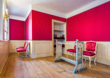 Schloss und Schlossgarten Schwetzingen - Schloss - Nordflügel, Nord-Süd-Teil - Schlosskapelle - Hofloge - Von Nordwest - Blick in die Hofloge des Kurfürstenpaars Carl Theodor (1724-1799, reg. 1742-1799) und Elisabeth Auguste (1721-1794) sowie auf einen Betstuhl und Stühle (Schlosskapelle: Länge ca. 14 Meter, Breite ca. 10 Meter, Höhe: bis unter das Dach, Achsen: 6, Eingang: Ostseite; Bauzeit: zwischen 1698 und 1715; Architekten: Johann Adam Breunig, Simon Sarto; Umbau innen im klassizistischen Stil: 1804-1806, Architekt: Friedrich Weinbrenner) (aufgenommen im Dezember 2025, um die Mittagszeit) Schloss und Schlossgarten Schwetzingen - Schloss - Nordflügel, Nord-Süd-Teil - Schlosskapelle - Hofloge - Von Nordwest - Blick in die Hofloge des Kurfürstenpaars Carl Theodor (1724-1799, reg. 1742-1799) und Elisabeth Auguste (1721-1794) sowie auf einen Betstuhl und Stühle (Schlosskapelle: Länge ca. 14 Meter, Breite ca. 10 Meter, Höhe: bis unter das Dach, Achsen: 6, Eingang: Ostseite; Bauzeit: zwischen 1698 und 1715; Architekten: Johann Adam Breunig, Simon Sarto; Umbau innen im klassizistischen Stil: 1804-1806, Architekt: Friedrich Weinbrenner) (aufgenommen im Dezember 2025, um die Mittagszeit)