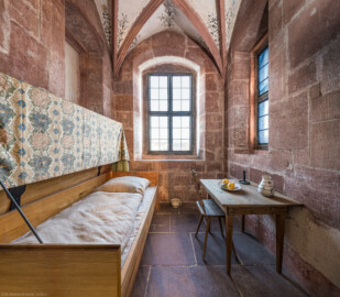Schloss und Schlossgarten Schwetzingen - Schloss - Mittelbau - Von innen - 1. Obergeschoss - Appartment des Kurfürsten - Lakaienschlafzimmer - Von Westen - Blick nach Osten in das spätgotische Turmzimmer; Nutzung als Schlafraum für den Kammerlakaien (Zimmer: im Zustand 1521, Teil des Standerkers, Zimmer mit Kreuzrippengewölbe, Gewölbe mit vegetabiler Malerei, Gewölbeschlussstein mit dreiteiligem pfälzischem Wappen, Wände mit Resten von farbiger Renaissancemalerei, Trennwand aus Holz mit Lunettenfenstern zum ersten Vorzimmer) (aufgenommen im Dezember 2025, am Nachmittag)