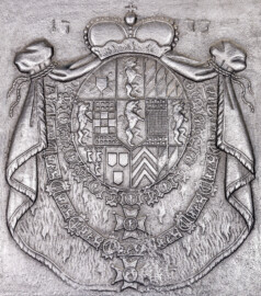 Schloss und Schlossgarten Schwetzingen - Schloss - Mittelbau - Von innen - 1. Obergeschoss - Appartment des Kurfürsten - Erstes Vorzimmer - Südwand - Kaminplatte des Kamins mit dem kurpfälzischen Prunkwappen von 1773; das großes Allianzwappen von Carl Theodor zeigt u.a.: Pfälzer Löwe, Löwe von Jülich, Löwe von Berg, Löwe der Grafschaft Veldenz, Lilienhaspel von Kleve, bayerische Raute, Schachbrett der Grafschaft Sponheim, Dreiberg von Bergen op Zoom, Sparren der Grafschaft Ravensberg, darunter zwei Ordensketten (wohl des Ordens vom Goldenen Vlies und des Hubertusordens) (aufgenommen im Dezember 2025, am späten Vormittag)