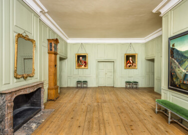 Schloss und Schlossgarten Schwetzingen - Schloss - Mittelbau - Von innen - 1. Obergeschoss - Appartment des Kurfürsten - Erstes Vorzimmer - Von Osten - Blick von der Ostwand nach Westen in das erste Vorzimmer; die Tür links führt in das nordöstliche Treppenhaus, die Tür in der Mitte in das zweite Vorzimmer, die Tür rechts davon führt auf den Gang der Empore der Schlosskapelle; das Porträt links zeigt Kurfürst Carl Theodor (1724-1799, reg. 1742-1799; Maler: Heinrich Carl Brandt (1724-1787); Datierung: um 1767), das Porträt rechts Elisabeth Auguste von Pfalz-Sulzbach (1721-1794; Maler: Heinrich Carl Brandt (1724-1787); Datierung: um 1767), das Gemälde ganz rechts zeigt eine sog. "eingestellten Jagd" unter Kurfürst Karl III. Philipp (1661-1742, reg. 1716-1742; Maler und Datierung: unbekannt) (aufgenommen im Dezember 2025, am Nachmittag) Schloss und Schlossgarten Schwetzingen - Schloss - Mittelbau - Von innen - 1. Obergeschoss - Appartment des Kurfürsten - Erstes Vorzimmer - Von Osten - Blick von der Ostwand nach Westen in das erste Vorzimmer; die Tür links führt in das nordöstliche Treppenhaus, die Tür in der Mitte in das zweite Vorzimmer, die Tür rechts davon führt auf den Gang der Empore der Schlosskapelle; das Porträt links zeigt Kurfürst Carl Theodor (1724-1799, reg. 1742-1799; Maler: Heinrich Carl Brandt (1724-1787); Datierung: um 1767), das Porträt rechts Elisabeth Auguste von Pfalz-Sulzbach (1721-1794; Maler: Heinrich Carl Brandt (1724-1787); Datierung: um 1767), das Gemälde ganz rechts zeigt eine sog. "eingestellten Jagd" unter Kurfürst Karl III. Philipp (1661-1742, reg. 1716-1742; Maler und Datierung: unbekannt) (aufgenommen im Dezember 2025, am Nachmittag)