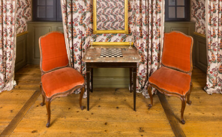 Schloss und Schlossgarten Schwetzingen - Schloss - Mittelbau - Von innen - 1. Obergeschoss - Appartment des Kurfürsten - Zweites Vorzimmer - Nordwand - Blick auf einen Spieltisch, daneben zwei Stühle (Nußbaum, geschnitzt, Straßburg, um 1750) (aufgenommen im Dezember 2025, am Nachmittag)