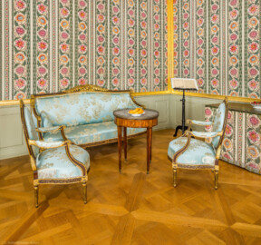 Schloss und Schlossgarten Schwetzingen - Schloss - Mittelbau - Von innen - 1. Obergeschoss - Appartment des Kurfürsten - Schlafzimmer - Ost- und Südwand - Von Nordwest - Blick Richtung südöstliche Ecke auf die Sitzgruppe, bestehend aus einem Canapé, zwei Medaillon-Sesseln und einm Tisch), im Hintergrund rechts ein Notenpult und ein Toilettentisch (aufgenommen im Januar 2026, am frühen Nachmittag)