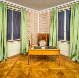 Schloss und Schlossgarten Schwetzingen - Schloss - Mittelbau - Von innen - 1. Obergeschoss - Appartment des Kurfürsten - Arbeitskabinett - Von Südwest - Blick vom Durchgang zum Arbeitskabinett in die Nordostecke des Raums; auf dem Schreibtisch links eine Nachbildung der Trajanssäule in Rom, rechts davon eine Schreibzeuggarnitur (Herkunft: Porzellan-Manufaktur Meissen) (aufgenommen im Februar 2026, am frühen Nachmittag)