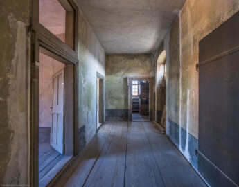 Schloss und Schlossgarten Schwetzingen - Schloss - Mittelbau - Von innen - 3. Obergeschoss - Südlicher Gang - Von Westen - Blick von der Tür zum Raum 230 nach Osten in den südlichen Gang; links vorne die Tür zum Raum 228, links hinten die Tür zum Raum 227; die Tür in der Mitte führt in den Schacht des südlichen Turms; die Tür hinten rechts (bei den Hölzern, nur teilweise sichtbar) führte ehemals (heute zugemauert) in den Dachstuhl des Querbaus des Südflügels / Hofdamenflügels; die Tür vorne rechts führt in den alten Treppenturm (aufgenommen im März 2026, am frühen Nachmittag) Schloss und Schlossgarten Schwetzingen - Schloss - Mittelbau - Von innen - 3. Obergeschoss - Südlicher Gang - Von Westen - Blick von der Tür zum Raum 230 nach Osten in den südlichen Gang; links vorne die Tür zum Raum 228, links hinten die Tür zum Raum 227; die Tür in der Mitte führt in den Schacht des südlichen Turms; die Tür hinten rechts (bei den Hölzern, nur teilweise sichtbar) führte ehemals (heute zugemauert) in den Dachstuhl des Querbaus des Südflügels / Hofdamenflügels; die Tür vorne rechts führt in den alten Treppenturm (aufgenommen im März 2026, am frühen Nachmittag)
