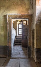 Schloss und Schlossgarten Schwetzingen - Schloss - Mittelbau - Von innen - 3. Obergeschoss - Südlicher Turm / Südlicher Gang - Von Westen - Blick vom südlichen Gang nach Osten in den Raum des südlichen Turms; links eine kleine Treppe hoch zum Fenster, rechts ein holzverkleideter Seilschacht; drei kugelförmige Antriebsgewichte an drei Seilen mit Umlenkrollen im Seilschacht treiben das Uhrwerk und das Schlagwerk der alten Schlossuhr im Dachgeschoss des Turms an (Turmuhr von Johann Jacob Möllinger (1695-1763) mit Viertel- und Stundenschlag, errichtet 1763, stillgelegt 1968) (aufgenommen im März 2026, am Nachmittag) Schloss und Schlossgarten Schwetzingen - Schloss - Mittelbau - Von innen - 3. Obergeschoss - Südlicher Turm / Südlicher Gang - Von Westen - Blick vom südlichen Gang nach Osten in den Raum des südlichen Turms; links eine kleine Treppe hoch zum Fenster, rechts ein holzverkleideter Seilschacht; drei kugelförmige Antriebsgewichte an drei Seilen mit Umlenkrollen im Seilschacht treiben das Uhrwerk und das Schlagwerk der alten Schlossuhr im Dachgeschoss des Turms an (Turmuhr von Johann Jacob Möllinger (1695-1763) mit Viertel- und Stundenschlag, errichtet 1763, stillgelegt 1968) (aufgenommen im März 2026, am Nachmittag)