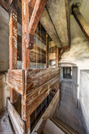 Schloss und Schlossgarten Schwetzingen - Schloss - Mittelbau - Von innen - 3. Obergeschoss - Südlicher Turm - Von Nordost - Blick vom Fenster nach Südwest in den Raum des südlichen Turms; links ein holzverkleideter Seilschacht; drei kugelförmige Antriebsgewichte an drei Seilen mit Umlenkrollen im Seilschacht treiben das Uhrwerk und das Schlagwerk der alten Schlossuhr im Dachgeschoss des Turms an (Turmuhr von Johann Jacob Möllinger (1695-1763) mit Viertel- und Stundenschlag, errichtet 1763, stillgelegt 1968); rechts unten eine kleine Treppe hoch zum Fenster; rechts hinten der südliche Gang (aufgenommen im März 2026, am Nachmittag)