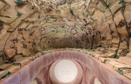 Schloss und Schlossgarten Schwetzingen - Garten - Badhausanlage - Perspektiv - Grotte - Von unten - Zentraler Blick von der Mitte der Grotte nach oben in die Felsengrotte, geschmückt mit Muscheln, Algen, Halbedelsteinen und Mineralkristallen; unten im Bild (im Süden) die Rundbögen und die Kuppel der zentralen Halle, oben im Bild (im Norden) die Öffnung zur Vorgrotte, die den Blick auf das Gemälde ("Ende der Welt") freigibt (Perspektiv: Abmessungen Länge x Breite x Höhe: Laubengang ca. 40 x 3,5 x 4,5 Meter, Bau ca. 16 x 4,5 bis 11 x 6,5 Meter, Bildwand ca. 9 x 1 x 7,5 Meter; Fertigstellung: 1775, Gesamtinstandsetzung: 1988-1991, Restaurierung Laubengang: 2022; Architekt: Nicolas de Pigage) (aufgenommen im April 2026, am späten Nachmittag)