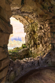 Schloss und Schlossgarten Schwetzingen - Garten - Badhausanlage - Perspektiv - Vorgrotte - Von Südwest - Blick von der Westseite der Grotte auf die Vorgrotte und auf das Gemälde "Das Ende der Welt" an der gewölbten Bildwand; Vorgrotte angebaut mit Steinen aus Tuff und Gips, (ehemals) mit Wasser von oben berieselt, unten ein kleines Wasserbecken aus Tuffstein, unten vorne und hinten eiserne Schilfblätter  (Perspektiv: Abmessungen Länge x Breite x Höhe: Laubengang ca. 40 x 3,5 x 4,5 Meter, Bau ca. 16 x 4,5 bis 11 x 6,5 Meter, Bildwand ca. 9 x 1 x 7,5 Meter; Fertigstellung: 1775, Gesamtinstandsetzung: 1988-1991, Restaurierung Laubengang: 2022; Architekt: Nicolas de Pigage) (aufgenommen im April 2026, am frühen Nachmittag)