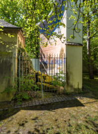 Schloss und Schlossgarten Schwetzingen - Garten - Badhausanlage - Perspektiv - Von Osten - Blick vom Arboretum nach Westen auf den Bau des Perspektivs mit der Grotte (links) und auf die Mauer der Bildwand (rechts) mit dem Gemälde "Das Ende der Welt" (Perspektiv: Abmessungen Länge x Breite x Höhe: Laubengang ca. 40 x 3,5 x 4,5 Meter, Bau ca. 16 x 4,5 bis 11 x 6,5 Meter, Bildwand ca. 9 x 1 x 7,5 Meter; Fertigstellung: 1775, Gesamtinstandsetzung: 1988-1991, Restaurierung Laubengang: 2022; Architekt: Nicolas de Pigage) (aufgenommen im April 2026, am Nachmittag)