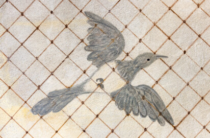 Schloss und Schlossgarten Schwetzingen - Garten - Badhausanlage - Perspektiv - Östlicher Flügel - Von unten - Blick auf einen fliegenden Vogel unter einem Gitter, darüber ein bewölkter Himmel, als Illusion einer Voliere (Perspektiv: Abmessungen Länge x Breite x Höhe: Laubengang ca. 40 x 3,5 x 4,5 Meter, Bau ca. 16 x 4,5 bis 11 x 6,5 Meter, Bildwand ca. 9 x 1 x 7,5 Meter; Fertigstellung: 1775, Gesamtinstandsetzung: 1988-1991, Restaurierung Laubengang: 2022; Architekt: Nicolas de Pigage) (aufgenommen im April 2026, am Nachmittag)
