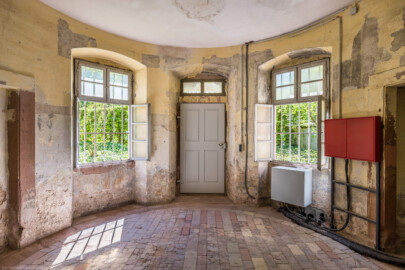 Schloss und Schlossgarten Schwetzingen - Garten - Badhausanlage - Badhausküche - Von innen - Rotunde - Von Nordost - Blick in den runden Eingangsraum, auf die Eingangstür (Mitte) sowie ganz links und ganz rechts auf ehemalige Wandschränke  (Gesamter Bau: Länge x Breite (winkelförmig) ca. 13 x 11 Meter, Höhe (über Rotunde) ca. 8 Meter; Raum: Durchmesser ca. 5 Meter, Höhe ca. 3 Meter; Architekt: Nicolas de Pigage (1723-1796); Bauzeit: 1768-1772, Dachinstandsetzung: 1983-1985, Instandsetzung: 2013-2015) (aufgenommen im April 2026, am Nachmittag)