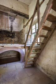 Schloss und Schlossgarten Schwetzingen - Garten - Badhausanlage - Badhausküche - Von innen - Heizraum - Von Südwest - Blick von der Tür in den Heizraum, auf die Empore und auf die Holzstiege in den Dachraum; unter der Empore die große Feuerungsanlage, darüber die wandbreite Kaminabzugshaube; auf der Empore stand wohl ein großer Kessel zur Warmwasseraufbereitung für das Wasserbecken des Badhauses (Gesamter Bau: Länge x Breite (winkelförmig) ca. 13 x 11 Meter, Höhe (über Rotunde) ca. 8 Meter; Raum: Länge x Breite x Höhe ca. 6 x 6 x 5,5 Meter; Architekt: Nicolas de Pigage (1723-1796); Bauzeit: 1768-1772, Dachinstandsetzung: 1983-1985, Instandsetzung: 2013-2015) (aufgenommen im April 2026, am frühen Nachmittag) Schloss und Schlossgarten Schwetzingen - Garten - Badhausanlage - Badhausküche - Von innen - Heizraum - Von Südwest - Blick von der Tür in den Heizraum, auf die Empore und auf die Holzstiege in den Dachraum; unter der Empore die große Feuerungsanlage, darüber die wandbreite Kaminabzugshaube; auf der Empore stand wohl ein großer Kessel zur Warmwasseraufbereitung für das Wasserbecken des Badhauses (Gesamter Bau: Länge x Breite (winkelförmig) ca. 13 x 11 Meter, Höhe (über Rotunde) ca. 8 Meter; Raum: Länge x Breite x Höhe ca. 6 x 6 x 5,5 Meter; Architekt: Nicolas de Pigage (1723-1796); Bauzeit: 1768-1772, Dachinstandsetzung: 1983-1985, Instandsetzung: 2013-2015) (aufgenommen im April 2026, am frühen Nachmittag)