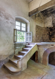 Schloss und Schlossgarten Schwetzingen - Garten - Badhausanlage - Badhausküche - Von innen - Heizraum - Von Südost - Blick von der Tür in den Heizraum und auf die Treppe zur Empore; rechts die Empore, darunter die große Feuerungsanlage, darüber die wandbreite Kaminabzugshaube; auf der Empore stand wohl ein großer Kessel zur Warmwasseraufbereitung für das Wasserbecken des Badhauses (Gesamter Bau: Länge x Breite (winkelförmig) ca. 13 x 11 Meter, Höhe (über Rotunde) ca. 8 Meter; Raum: Länge x Breite x Höhe ca. 6 x 6 x 5,5 Meter; Architekt: Nicolas de Pigage (1723-1796); Bauzeit: 1768-1772, Dachinstandsetzung: 1983-1985, Instandsetzung: 2013-2015) (aufgenommen im April 2026, am frühen Nachmittag) Schloss und Schlossgarten Schwetzingen - Garten - Badhausanlage - Badhausküche - Von innen - Heizraum - Von Südost - Blick von der Tür in den Heizraum und auf die Treppe zur Empore; rechts die Empore, darunter die große Feuerungsanlage, darüber die wandbreite Kaminabzugshaube; auf der Empore stand wohl ein großer Kessel zur Warmwasseraufbereitung für das Wasserbecken des Badhauses (Gesamter Bau: Länge x Breite (winkelförmig) ca. 13 x 11 Meter, Höhe (über Rotunde) ca. 8 Meter; Raum: Länge x Breite x Höhe ca. 6 x 6 x 5,5 Meter; Architekt: Nicolas de Pigage (1723-1796); Bauzeit: 1768-1772, Dachinstandsetzung: 1983-1985, Instandsetzung: 2013-2015) (aufgenommen im April 2026, am frühen Nachmittag)