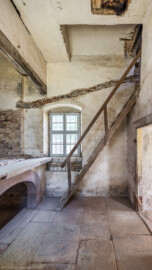 Schloss und Schlossgarten Schwetzingen - Garten - Badhausanlage - Badhausküche - Von innen - Heizraum - Von Westen - Blick von der Südwestecke in den Heizraum, auf  die Holzstiege in den Dachraum und auf die Empore; unter der Empore die große Feuerungsanlage, darüber die wandbreite Kaminabzugshaube; auf der Empore stand wohl ein großer Kessel zur Warmwasseraufbereitung für das Wasserbecken des Badhauses (Gesamter Bau: Länge x Breite (winkelförmig) ca. 13 x 11 Meter, Höhe (über Rotunde) ca. 8 Meter; Raum: Länge x Breite x Höhe ca. 6 x 6 x 5,5 Meter; Architekt: Nicolas de Pigage (1723-1796); Bauzeit: 1768-1772, Dachinstandsetzung: 1983-1985, Instandsetzung: 2013-2015) (aufgenommen im April 2026, am Nachmittag)