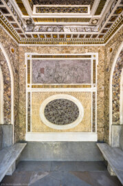 Schloss und Schlossgarten Schwetzingen - Garten - Badhausanlage - Östliches Achathäuschen - Von innen - Ostwand - Blick vom Eingang nach Osten in den Raum; oberhalb der Bildmitte ein Bleirelief mit der Darstellung eines Erotentanzes um die Statue der Göttin Flora, unterhalb der Bildmitte eine ovale Kartusche, inkrustiert mit violetten Amethysten, links und rechts Ruhebänke, ganz oben die reich verzierte Decke; die Wände sind mit Tropfenstuck, Steinen, Mineralien und Kristallen inkrustiert (Bildhauer: Franz Conrad Linck (1730-1793), Datierung: um 1770-1775) (Achathäuschen: Abmessungen Breite x Tiefe x Höhe 3,2 x 3,0 x 6,4 Meter, Innenraum Breite x Tiefe ca. 2 x 2 Meter; Architekt: Nicolas de Pigage, Fertigstellung: um 1775, Instandsetzung: 1991 - 1995) (aufgenommen im Mai 2026, am Vormittag)