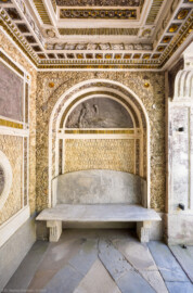 Schloss und Schlossgarten Schwetzingen - Garten - Badhausanlage - Östliches Achathäuschen - Von innen - Südwand - Blick von der nördlichen Ruhebank nach Süden in den Raum, auf die Decke, auf die südliche Wand, auf die Lünette mit einem Bleirelief der Darstellung eines bärtigen Flussgottes sowie auf die südliche Bank (Bildhauer: Franz Conrad Linck (1730-1793), Datierung: um 1770-1775) (Achathäuschen: Abmessungen Breite x Tiefe x Höhe 3,2 x 3,0 x 6,4 Meter, Innenraum Breite x Tiefe ca. 2 x 2 Meter; Architekt: Nicolas de Pigage, Fertigstellung: um 1775, Instandsetzung: 1991 - 1995) (aufgenommen im Mai 2026, am Vormittag)