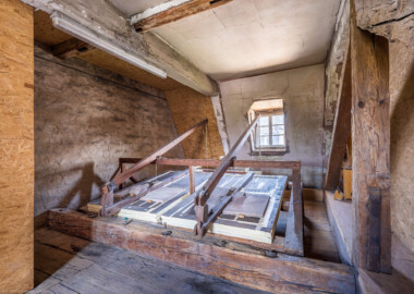Schloss und Schlossgarten Schwetzingen - Schloss - Nordflügel, Querbau - Dachgeschoss - Raum der Windanlage, oberhalb der Orgel - Von Westen  - Blick in den Raum mit der historischen mechanischen Windanlage der Orgel; durch Ziehen an den Seilen (im Raum neben der Orgel unterhalb) erzeugt das Windwerk Druckluft (den Orgelwind), die zu den Orgelpfeifen geleitet wird und dort Töne erzeugen kann  (Orgelbauer: Andreas Ubhauser (1765-1822), Bauzeit: 1806, umfassende Restaurierung: 1980-1982, Originalteile: ca. 90 Prozent;  Windwerk: Schleifladen und elektrisches Gebläse, Register: 10, Manuale: 1 / C-f3, Pedale: 1 / C-f0; Orgelpfeifen aus Zinn, Tastatur aus Ebenholz) (aufgenommen im Juli 2026, am frühen Nachmittag)