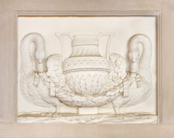 Schloss und Schlossgarten Schwetzingen - Garten - Badhaus - Von innen - Östliches Vorzimmer - Südwand - Supraporte - Von Norden - Blick auf die Supraporte: ein Relief mit einer Vase, von zwei Schwänen flankiert; in den Schnäbeln der Schwäne Lorbeergirlanden, Vase mit eckigen Henkeln, Vasenhals mit geschwungenen Kanneluren, Vasenbauch mit lanzettförmigen Lorbeerblättern, darüber Manschetten mit Perlband und gegenläufigem Wellenband (Gesamter Bau: Länge x Breite ca. 18 x 14 Meter, Höhe ca. 10 Meter; Architekt: Nicolas de Pigage (1723-1796); Bauzeit: 1768-1772; Gesamtinstandsetzung innen und außen: 1999-2006) (aufgenommen im Juli 2026, am Nachmittag)