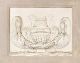 Schloss und Schlossgarten Schwetzingen - Garten - Badhaus - Von innen - Östliches Vorzimmer - Nordwand - Supraporte - Von Süden - Blick auf die Supraporte: ein Relief mit einer Vase, von zwei Schwänen flankiert; in den Schnäbeln der Schwäne Lorbeergirlanden, Vase mit eckigen Henkeln, Vasenhals mit geschwungenen Kanneluren, Vasenbauch mit lanzettförmigen Lorbeerblättern, darüber Manschetten mit Perlband und gegenläufigem Wellenband (Gesamter Bau: Länge x Breite ca. 18 x 14 Meter, Höhe ca. 10 Meter; Architekt: Nicolas de Pigage (1723-1796); Bauzeit: 1768-1772; Gesamtinstandsetzung innen und außen: 1999-2006) (aufgenommen im Juli 2026, am späten Nachmittag)