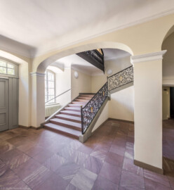 Schloss und Schlossgarten Schwetzingen - Garten - Gesandtenhaus (ehemaliges Prinzenhaus) / Amtsgericht - Von Innen - Treppenhaus / Erdgeschoss - Von Nordwest - Blick in das Treppenhaus, auf die dreiläufige, zweimal abgewinkelte Sandsteintreppe mit zwei Zwischenpodesten sowie auf das schmiedeeiserne, verzierte Eisengeländer mit den verschlungenen Monogrammen "CP" für Kurfürst Carl Philipp (1661-1742, reg. 1716-1742) (aufgenommen im August 2026, am Nachmittag)