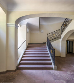 Schloss und Schlossgarten Schwetzingen - Garten - Gesandtenhaus (ehemaliges Prinzenhaus) / Amtsgericht - Von Innen - Treppenhaus / Erdgeschoss - Von Norden - Blick vom Haupteingang in das Treppenhaus, auf die dreiläufige, zweimal abgewinkelte Sandsteintreppe mit zwei Zwischenpodesten sowie auf das schmiedeeiserne, verzierte Eisengeländer mit den verschlungenen Monogrammen "CP" für Kurfürst Carl Philipp (1661-1742, reg. 1716-1742) (aufgenommen im August 2026, am Nachmittag)