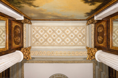 Schloss und Schlossgarten Schwetzingen - Garten - Badhaus - Von innen - Schreibzimmer - Alkoven - Von unten - Blick nach oben auf die Decke des Alkoven; Westen ist im Bild oben; zwei korinthische Säulen und zwei Pilaster tragen das Gebälk der Decke (Decke der Nische ist niedriger als Decke des Zimmers);  Deckenspiegel eingerahmt von Rosettenfries, Milleraies-Band und Rosettenband; Kassettendecke aus gedrehten Bändern mit Blütenrosetten an den Kreuzungspunkten und in den Rautenfeldern (Gesamter Bau: Länge x Breite ca. 18 x 14 Meter, Höhe ca. 10 Meter; Architekt: Nicolas de Pigage (1723-1796); Bauzeit: 1768-1772; Gesamtinstandsetzung innen und außen: 1999-2006) (aufgenommen im Oktober 2026, am frühen Nachmittag)