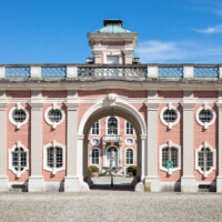 Schloss Bruchsal - Von Außen - Von Westen - Blick vom Ehrenhof auf die Westfassade des Torwachtgebäudes und hinter dem Durchgang auf die Westfassade des Kanzleibaus (aufgenommen im April 2018, am Nachmittag)