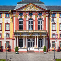Schloss Bruchsal - Hauptbau - Von Außen / Von Osten / Hofseite - Blick vom Ehrenhof auf die Ostfassade mit dem Mittelrisalit, dem Balkon, dem Fürstensaal und dem Dreiecksgiebel (aufgenommen im Mai 2018, um die Mittagszeit)