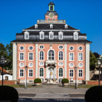 Schloss Bruchsal - Von Außen / Von Westen - Blick vom Durchgang des Torwachtgebäudes auf die Westfassade des Kanzleibaus, davor der Amalienbrunnen, auch „Schneckenbrunnen” genannt (aufgenommen im Juli 2018, am frühen Abend)