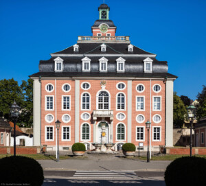 Schloss Bruchsal - Von Außen / Von Westen - Blick vom Durchgang des Torwachtgebäudes auf die Westfassade des Kanzleibaus, davor der Amalienbrunnen, auch „Schneckenbrunnen” genannt (aufgenommen im Juli 2018, am frühen Abend)