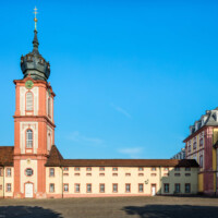 Schloss Bruchsal - Kirchturm / Finsterer Gang / Verbindungsgang - Von Außen / Von Osten - Blick vom ehemaligen südlichen Marstall (heute Parkplatz) auf den Kirchturm der Hofkirche und die Ostseite des Finsteren Gangs, links der Seminarbau / die Pagerie, rechts der Kirchenflügel / die Hofkirche (aufgenommen im August 2019, am Vormittag)