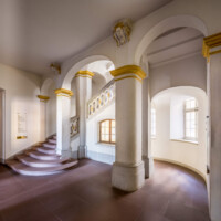 Schloss Bruchsal - Hauptbau / Corps de Logis - Von innen - Nordöstliche Dienertreppe - Erdgeschoss - Von Nordosten - Blick auf die Dienertreppe in das erste Obergeschoss (Zwischengeschoss), links die Tür zur Intrada (aufgenommen im September 2020, am Nachmittag)