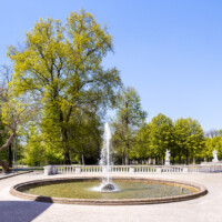 Schloss Bruchsal - Schlossterrasse - Von Osten - Blick vom südlichen Eingang (zwischen südlicher Orangerie und Hauptbau) auf einen der drei Springbrunnen, die Terrasse und den Garten (aufgenommen im April 2021, am frühen Nachmittag)