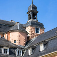 Schloss und Schlossgarten Schwetzingen - Schloss - Mittelbau - Von Südwest - Blick vom Verbindungsbau Küchenflügel zum Südlichen Zirkelbau nach oben auf den Südturm des Mittelbaus mit dem Dachreiter, den Glocken und dem Hemmerscher Fünfspitz, links daneben der Treppenturm; rechts die Westfassade des Südflügels / Hofkavaliersflügels (Mittelbau: Länge Westseite ca. 45 Meter, Breite Süd-/Nordseite ca. 38 Meter; Wiederaufbau / Erweiterung: 1698-1717; Architekten: Johann Adam Breunig, Simon Sarto) (aufgenommen im April 2023, am späten Nachmittag)