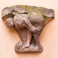 Schloss und Schlossgarten Schwetzingen - Schloss - Mittelbau - Hofseite - Von Osten - Blick auf die Spottfigur rechts des Bogens der Durchfahrt zum Garten; Datierung um 1470/80; Figur vermutlich ehemals als Säulenfuß genutzt; als Groteske streckt die Figur dem Betrachter sein Gesäß zum Spott entgegen (aufgenommen im Mai 2023, um die Mittagszeit)