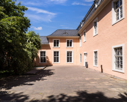 Schloss und Schlossgarten Schwetzingen - Schloss - Verbindungsbau Küchenbau-Zirkelbau / Alte Galerie - Südfassade, östliche Seite - Von Süden - Blick auf die Südfassade des Verbindungsgang zwischen dem Küchenflügel und dem Südlichen Zirkelbau, rechts die Westfassade des Küchenbaus (Verbindungsbau: Länge ca. 45 Meter, Breite ca. 8 Meter; Bauzeit: wohl um 1724; Architekt: unklar, evtl. Alessandro Galli da Bibiena (1686-1748) oder Johann Adam Breunig (1660-1727)) (aufgenommen im Mai 2023, am Nachmittag)