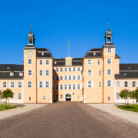 Schloss und Schlossgarten Schwetzingen - Schloss - Ostseite / Mittelbau / Süd- und Nordflügel / Ehrenhof - Von Osten - Zentraler Blick vom Ehrenhof nach Westen auf den Mittelbau mit dem Süd- und Nordturm und der Durchfahrt in den Garten sowie auf den Südflügel / Hofkavaliersflügel (links) und den Nordflügel / Hofdamenflügel (rechts) (Mittelbau und Flügel: Wiederaufbau / Erweiterung: 1698-1717; Architekten: Johann Adam Breunig, Simon Sarto) (aufgenommen im Juli 2023, am Vormittag)