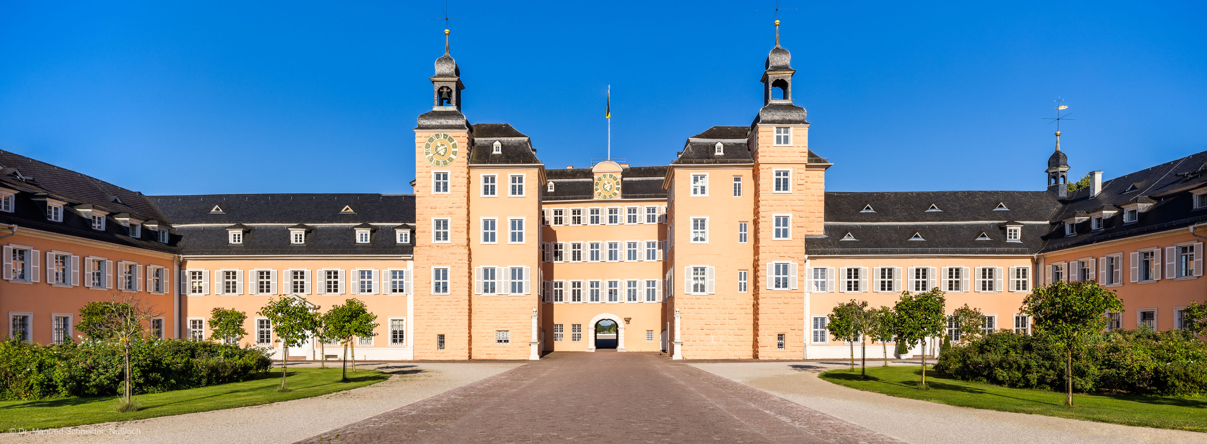 Schloss und Schlossgarten Schwetzingen - Schloss - Ostseite / Mittelbau / Süd- und Nordflügel / Ehrenhof - Von Osten - Zentraler Blick vom Ehrenhof nach Westen auf den Mittelbau mit dem Süd- und Nordturm und der Durchfahrt in den Garten sowie auf den Südflügel / Hofkavaliersflügel (links) und den Nordflügel / Hofdamenflügel (rechts) (Mittelbau und Flügel: Wiederaufbau / Erweiterung: 1698-1717; Architekten: Johann Adam Breunig, Simon Sarto) (aufgenommen im Juli 2023, am frühen Vormittag)