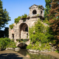 Schloss und Schlossgarten Schwetzingen - Garten - Römisches Wasserkastell - Von außen - Von Südost - Blick auf das Römische Wasserkastell; eine künstliche Ruine, teils in Tuffstein, mit zwei Türmen (westlich zwei-, östlich dreigeschossig), Mittelpartie mit großem Rundbogen, darüber eine Plattform, darunter ein Gewölbe mit Durchfluss des Leimbachs nach Norden; im östlichen Mittelgeschoss ein Tonrelief mit einer Wassernymphe von Franz Conrad Linck (1730-1793) (Kastell: Länge x Breite: ca. 15 x 8 Meter; Bauzeit: 1779-1780; Architekt: Nicolas de Pigage) (aufgenommen im September 2023, am späten Vormittag)