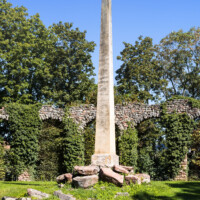 Schloss und Schlossgarten Schwetzingen - Garten - Obelisk, Nähe Römischem Wasserkastell - Von Süden - Blick vom südlichen Ufer des Leimbachs nach Norden auf den kleinen Hügel mit dem Obelisken, dahinter ein Teil des östlichen Aquädukts; der Obelisk dient als Denkmal für die in einer angenommenen Schlacht zwischen Römern und Germanen Gefallenen; die Skulptur markiert den Fundort von römisch-germanischen Gräbern, entdeckt 1777 bei Erdarbeiten zur Anlage des Arboretums (Obelisk: Höhe: ca. ? Meter; Bauzeit: 1779; Architekt: Nicolas de Pigage) (aufgenommen im September 2023, am späten Vormittag)