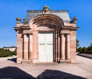 Schloss und Schlossgarten Schwetzingen - Garten - Südlicher Zirkelbau - Westlicher (Eck-) Pavillon - Westportal - Blick auf das Westportal, auf die Dreiviertelsäulen, die große Tür zum Steinhauersaal, darüber ein Korbbogen, zu beiden Seiten oben Blumenkörbe und ganz oben mittig eine Krone mit Kreuz (Gesamter Bau: Länge Bogen ca. 175 Meter, Breite zwischen ca. 11 und 18 Meter, 51 Achsen, 3 Pavillons (im Westen, im Osten und in der Mitte), 2 Zwischenbauten mit Sälen; Architekt: Franz Wilhelm Rabaliatti; Bauzeit: 1753-1754) (aufgenommen im September 2023, am Nachmittag)