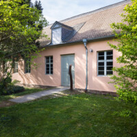 Schloss und Schlossgarten Schwetzingen - Garten - Baumagazin / Gartengeräte-Ausstellung - Von außen - Von Südost - Blick auf den Eingang zur Gartengeräte-Ausstellung (Bau Länge x Breite: ca. 47 x 10 Meter; Bauzeit: um 1774; Architekt: Nicolas de Pigage) (aufgenommen im April 2024, am späten Nachmittag)
