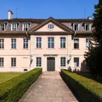 Schloss und Schlossgarten Schwetzingen - Garten - Gesandtenhaus (ehemaliges Prinzenhaus) / Amtsgericht - Von Südost - Blick von der Zeyherstraße auf die Südostfassade und das Portal des Gesandtenhauses (Nutzung: Wohnungen für Angehörige der kurfürstlichen Familie, ausländische Besucher, Nicolas de Pigage (1723-1796), Friedrich Ludwig Skell (1750-1823), Johann Michael Zeyher (1770-1843), Sterbeort von Johann Peter Hebel (1760-1826), ab 1805 Amtsgericht) (Bau: Länge x Breite: ca. 40 x 17 Meter; Bauzeit: um 1723; Architekt: unbekannt) (aufgenommen im Juli 2024, am späten Vormittag)