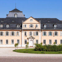 Schloss und Schlossgarten Schwetzingen - Schloss - Nordflügel / Hofkavaliersflügel - Von Süden - Blick vom Obergeschoss des Südflügels nach Norden auf den Ehrenhof, auf die Südfassade des Längsbaus (Mitte; heute genutzt vom Finanzamt) sowie auf die Ostfassade des Querbaus bzw. der Schlosskapelle (links); links der Mitte im Hintergrund das Dach des Oberen Wasserwerks (NordFlügel: L-förmig, Länge x Breite Längsbau ca. 50 x 14 Meter, Querbau ca. 15 x 12 Meter; Architekt: Johann Adam Breunig (1660-1727); Fertigstellung: 1710) (aufgenommen im August 2024, um die Mittagszeit)