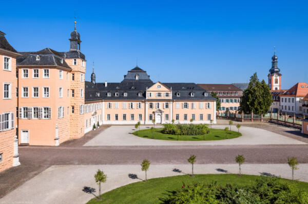 Schloss und Schlossgarten Schwetzingen - Schloss - Nordflügel / Hofkavaliersflügel - Von Süden - Blick vom Dachgeschoss des Südflügels nach Norden auf den Ehrenhof, den Mittelbau und den Nordflügel (den Hofkavaliersflügel, heute vom Finanzamt genutzt); v.l.n.r.: Anbau an südlichen Turm, nördliches Treppenhaus, Nordturm, Querbau des Nordflügels mit der Schlosskapelle, Längsbau des Nordflügels; ganz rechts der Turm von St. Pankratius; im Hintergrund links oberhalb der Bildmitte das Dach des Oberen Wasserwerks (NordFlügel: L-förmig, Länge x Breite Längsbau ca. 50 x 14 Meter, Querbau ca. 15 x 12 Meter; Architekt: Johann Adam Breunig (1660-1727); Fertigstellung: 1710) (aufgenommen im August 2024, am späten Vormittag)